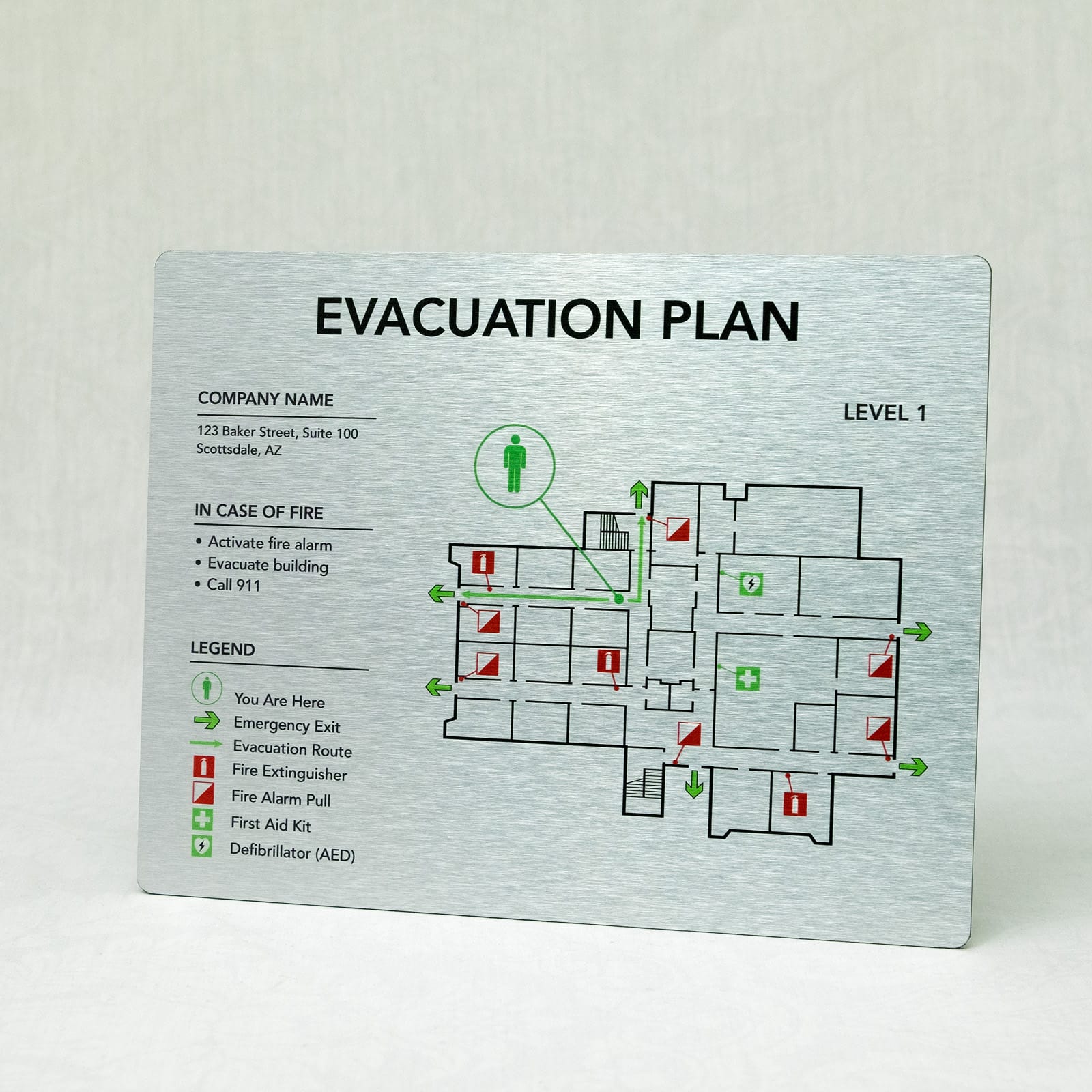 Brushed aluminum evacuation map showing level 1 floor layout with metallic finish, fire extinguishers, AED, first aid, and emergency exits