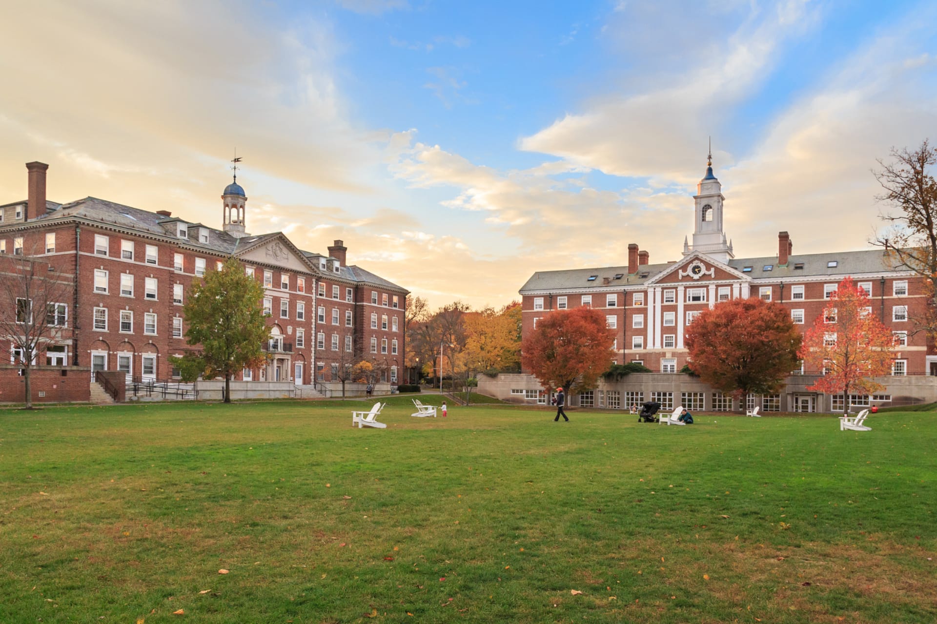 Historic university campus with red brick academic buildings, clock tower, and green lawn quad