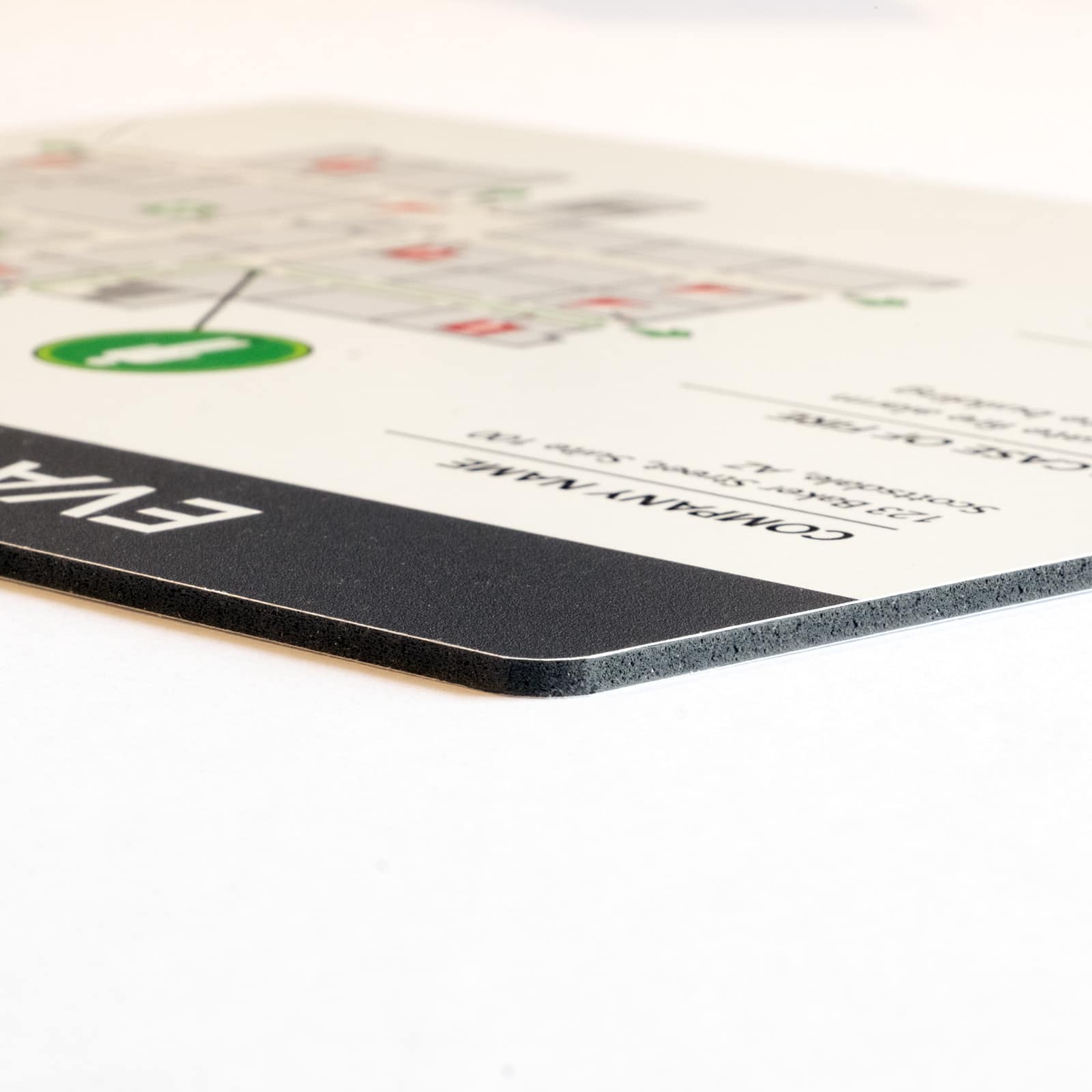 Angled view of Palboard PVC evacuation map showing gray expanded foam core, smooth white surface, and rounded corner detail