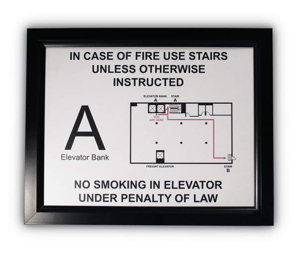 Black slide-in frame holding a New York City elevator landing sign reading in case of fire use stairs, with elevator bank A identification and floor plan